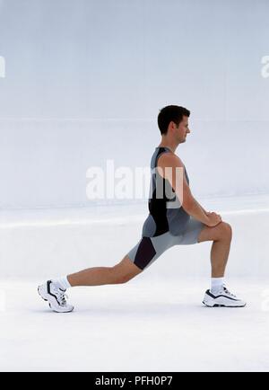 L'homme en short et débardeur exercice s'étendant de la scène, side view Banque D'Images