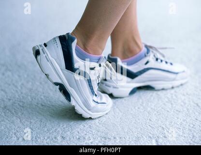 Pieds de femme dans les chaussures de sports, comité permanent sur la bille de pied avec le pied droit, close-up Banque D'Images