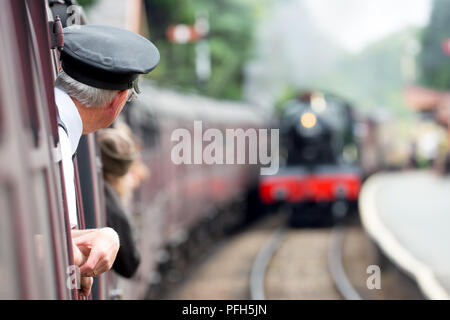 Vue arrière du contrôleur (prises en pension) vintage de transport en tant que station de train s'approche. Deuxième machine à vapeur s'approche. Banque D'Images