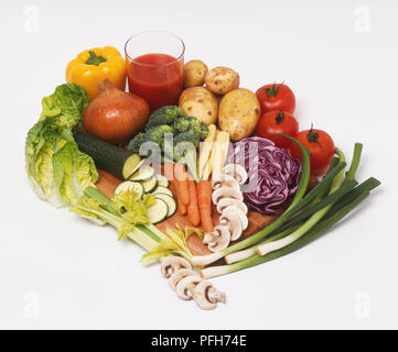 Sélection de légumes frais, y compris, le poivron, la courgette en rondelles, les carottes, les champignons tranchés, baby sweetcorn, brocoli, tomate, pomme de terre, oignon de printemps, salade, et un verre de jus de tomate Banque D'Images