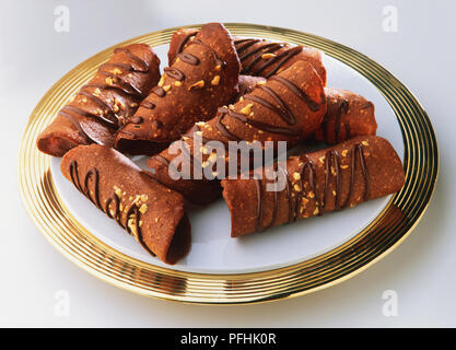 Tuiles au chocolat, chocolat-hazlenut arrosé curly s'enclenche sur plateau d'or, Close up. Banque D'Images
