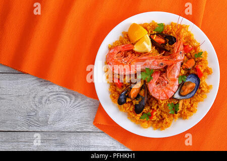 Partie de fruits de mer paella de Valence avec les langoustines, les moules sur le riz et crémeuse salé avec des épices et des tranches de citron sur l'assiette, vue de dessus Banque D'Images