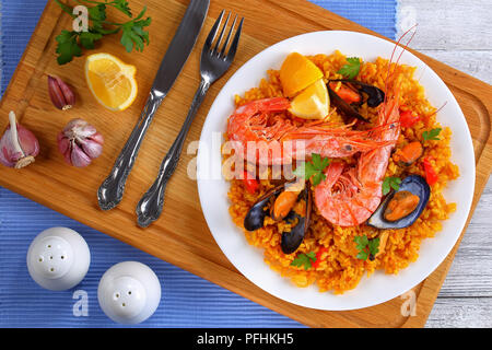 Partie de la paella de Valence de fruits de mer gastronomique avec des langoustines, des moules sur le riz et crémeuse salé avec des épices et des tranches de citron sur plaque, sur sol en bois ch Banque D'Images
