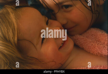 Deux jeune filles enveloppés dans des serviettes étreindre l'autre, Close up. Banque D'Images