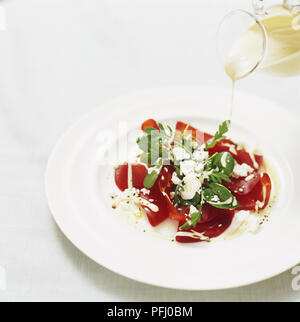 L'on verse plus de vinaigrette au fromage salade de bresaola, high angle view Banque D'Images