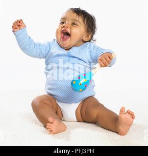 Baby Girl holding blue maracas dans une main et de rire Banque D'Images