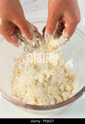 Paire de mains frottant la graisse et la farine ensemble dans un bol en verre, Close up. Banque D'Images