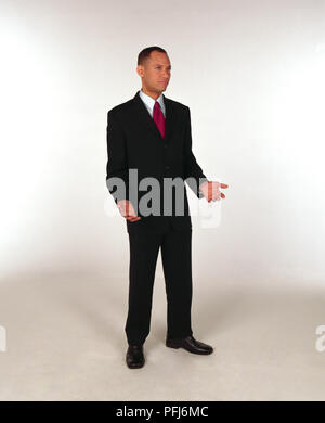 L'homme en costume d'affaires debout et tenant de ses paumes, vue de côté. Banque D'Images