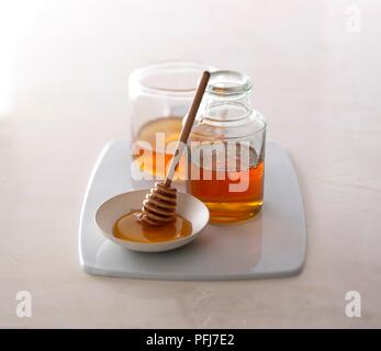 Deux pots de miel à côté de petit plat de miel avec balancier au miel Banque D'Images