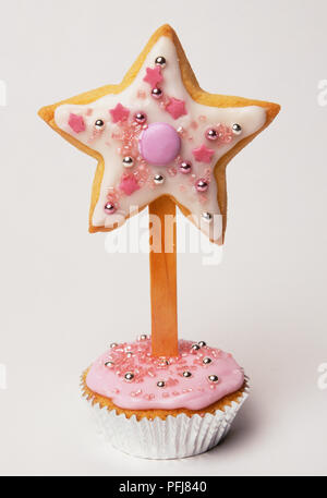 'Magic wand' créé à partir d'étoiles sur un biscuit en forme de stick inséré dans décorées cupcake, Close up. Banque D'Images