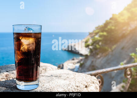 Cola glacé dans de grands verres de boisson contre la mer et le ciel bleu Banque D'Images