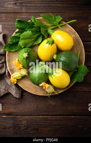 Les courgettes avec feuilles et fleurs sur fond rustique en bois foncé Banque D'Images