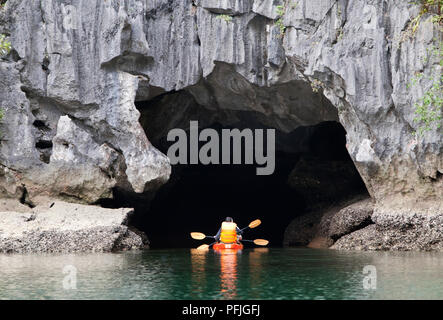 Cayakers entrant dans une grotte marine dans Ha Long Bay Banque D'Images