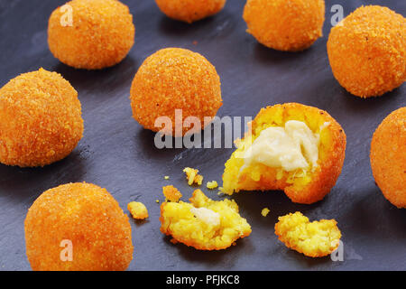 Délicieux chaud arancini italien - Boules de riz farcies de fromage fondu sur le plateau en ardoise noire, vue de dessus, close-up Banque D'Images