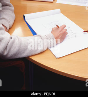 Personne assise au bureau à l'aide du bloc-notes et un crayon pour dessiner diagramme, high angle view. Banque D'Images