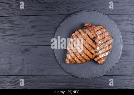 Deux steaks de boeuf grillé marbré de noir avec des rayures sur le plateau en ardoise sur table en bois noir, horizontal Vue de dessus Banque D'Images