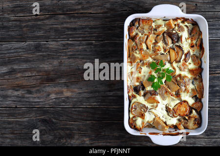 Ragoût délicieux avec les champignons sauvages en sauce à la crème aigre dans plat à gratin sur de vieilles planches en bois, vue du dessus Banque D'Images