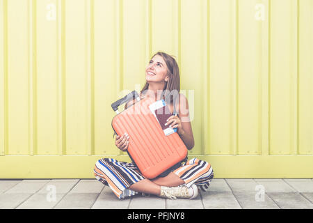 Woman traveler holding suitcase, passeport et billets contre fond jaune. Banque D'Images