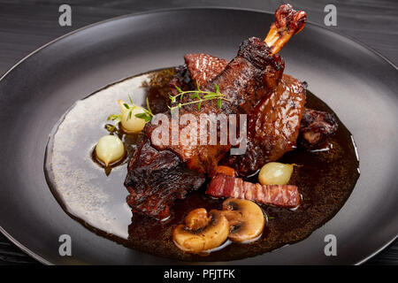 Close-up d'une partie de Coq au Vin - poulet savoureux poulet avec du vin, d'herbes, de champignons et de légumes servi sur la plaque noire, recette authentique français Banque D'Images