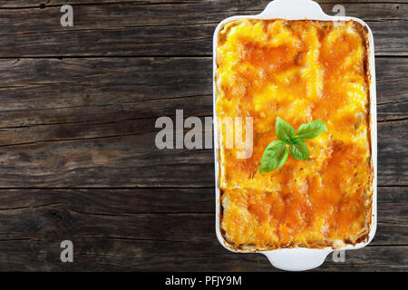 De délicieux plats italiens en couches avec feuilles de pâte à lasagne bolognaise, ragoût et garnie de fromage fondu et de feuilles de basilic frais dans le plat de cuisson, vue à partir de Banque D'Images