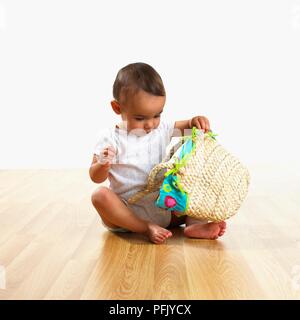 Baby Boy sitting on floor et jouer avec sac Banque D'Images