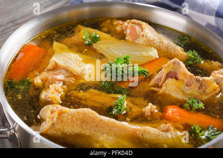 Close-up of delicious bouillon de poulet avec des morceaux de viande sur les os et coq de légumes dans une casserole en métal, vue d'en haut Banque D'Images