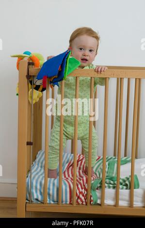 Baby Boy standing in cot, front view Banque D'Images