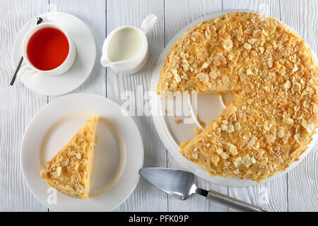 Délicieux morceau de gâteau de pâte feuilletée maison napoléon couches de crème pâtissière sur plaque blanche avec gâteau, tasse de thé et de lait à backgroun Banque D'Images