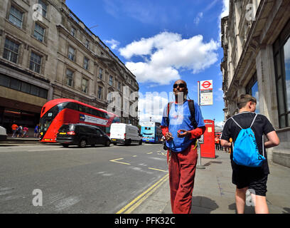 Londres, Angleterre, Royaume-Uni. Habillés de couleurs vives homme noir à écouter de la musique dans la rue Banque D'Images