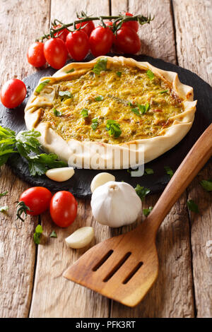 Épicé fait maison de tarte de légumes et d'herbes sur la table et d'ingrédients. vertical Banque D'Images