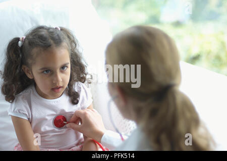 Female doctor holding stethoscope à la poitrine de fille Banque D'Images