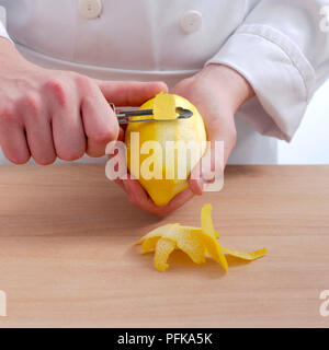 Main tenant peeler et citron, zeste de citron peeling off, close-up Banque D'Images