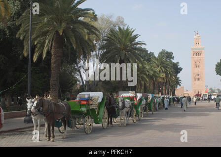 Le Maroc, Marrakech, calèches en attente dans une rangée près de minaret de la Koutoubia Banque D'Images