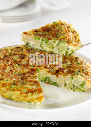 Tortilla aux pommes de terre, faites le brocoli et les pois, seule tranche d'être retirée à l'aide d'une spatule, close-up Banque D'Images