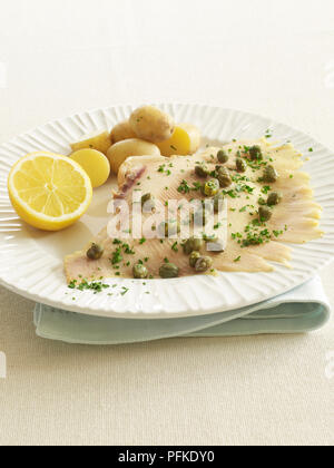 Raie pochée, Filet garni de câpres et de persil et servi avec des pommes de terre et citron, sur une assiette, close-up Banque D'Images