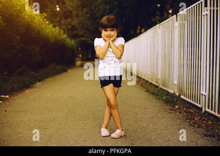 Portrait d'une petite fille, posant en parc en soirée. Banque D'Images