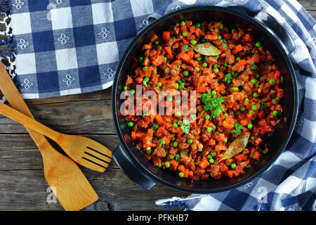 Délicieux ragoût classique avec la viande hachée, les légumes, les pois verts et les tomates dans le moule - matn ingrédient pour les pâtes à la bolognaise ou le pâté chinois, vue arrière Banque D'Images