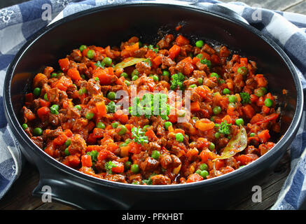 Close-up de délicieux ragoût classique avec de bœuf, les légumes, les pois verts et les tomates dans le moule - matn ingrédient pour les pâtes à la bolognaise ou shep Banque D'Images