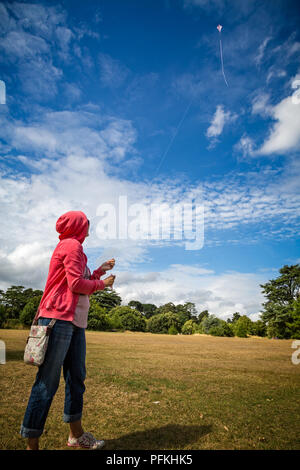Jeune dame flying kite contre ciel bleu profond à Bournemouth, Dorset, Royaume-Uni le 4 août 2014 Banque D'Images