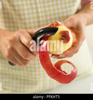 Woman peeling un Apple avec l'éplucheur, close-up Banque D'Images