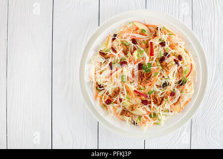 Peu de calories Pommes Canneberges et noix et salade de chou sur une assiette blanche sur une table en bois, vue du dessus Banque D'Images