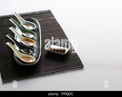 Les cuillères, contenant différents types de sauce de poisson thaï et vietnamien, sur bambou set de table Banque D'Images