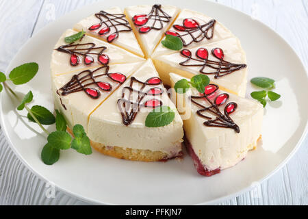 Close-up avec du chocolat et richement décoré gâteau au fromage gelée avec couche inférieure se compose de gâteau mousseline avec sauce aux baies, sur plateau blanc sur woo Banque D'Images