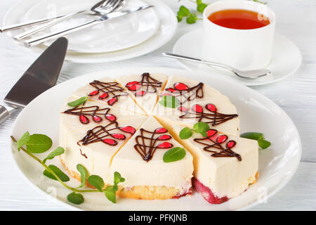 Délicieux gâteau au fromage avec couche inférieure se compose de gâteau mousseline était imbibé de sauce aux baies sucrées, sur plateau en bois blanc sur la table, tasse de thé et de pla Banque D'Images