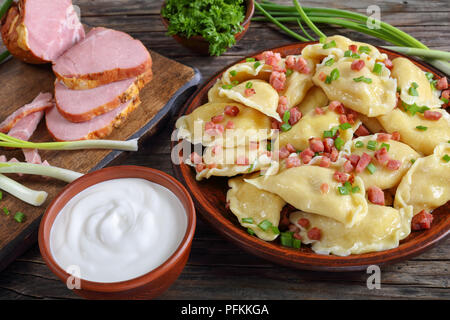 Délicieux chaud des pierogies ou quenelles avec purée de pommes de terre et de viande hachée finement saupoudré de remplissage de petits oignons et jambon. crème aigre et je Banque D'Images