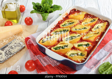 Close-up de la forme de la coquille pâtes farcies de fromage et épinards crémeux saupoudré de parmesan dans le plat de cuisson. fromage parmesan, râpé sur pap Banque D'Images