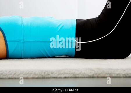 Young woman doing stretching exercice allongé sur le dos, mid section Banque D'Images