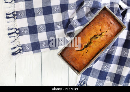 Des délicieux pain à la banane avec des noix et des morceaux de chocolat dans un moule à pain avec une serviette de cuisine en bois, sur le plan de recette authentique, vue à partir de Banque D'Images