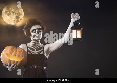 Fille avec faire Halloween citrouille d'attente et bougies contre la pleine lune. L'automne Banque D'Images