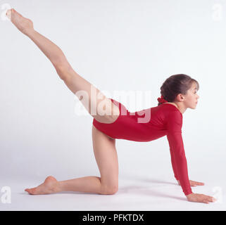 Gymnaste avec le genou gauche sur le sol, la jambe droite en l'air, side view Banque D'Images